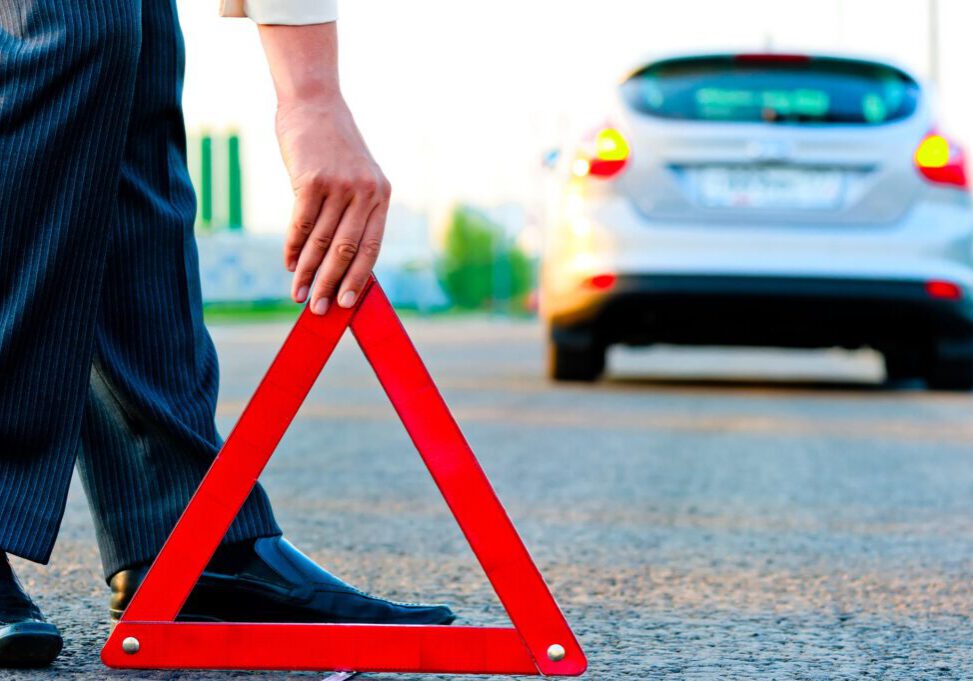 man putting road sign near his car